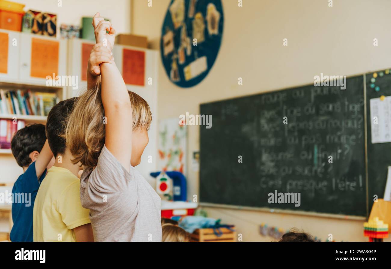 Concentrated 4-5 year old kids in classroom, child raising hand on ...