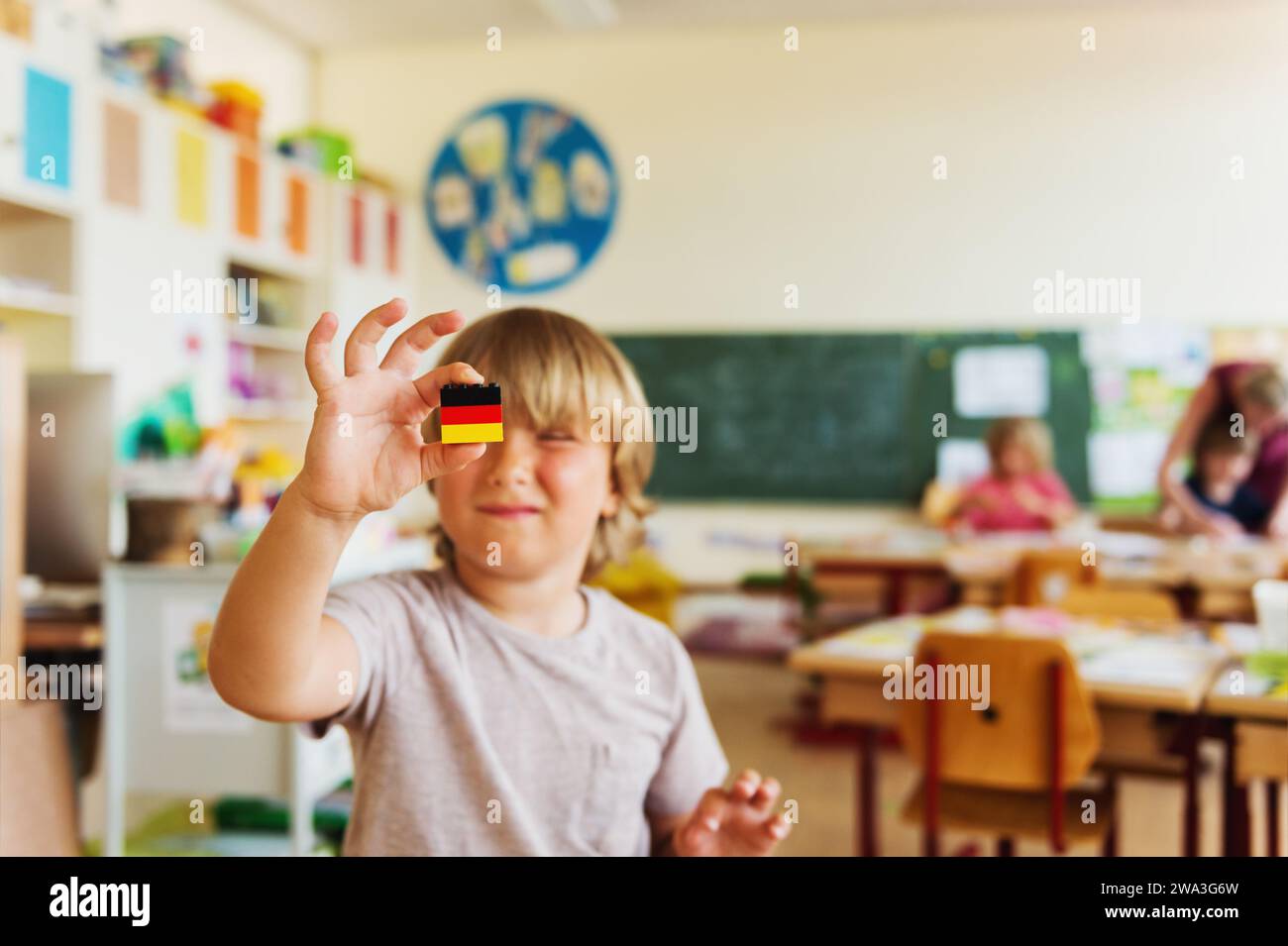 Cute little boy working in classroom, holding self made german flag, primary education Stock Photo
