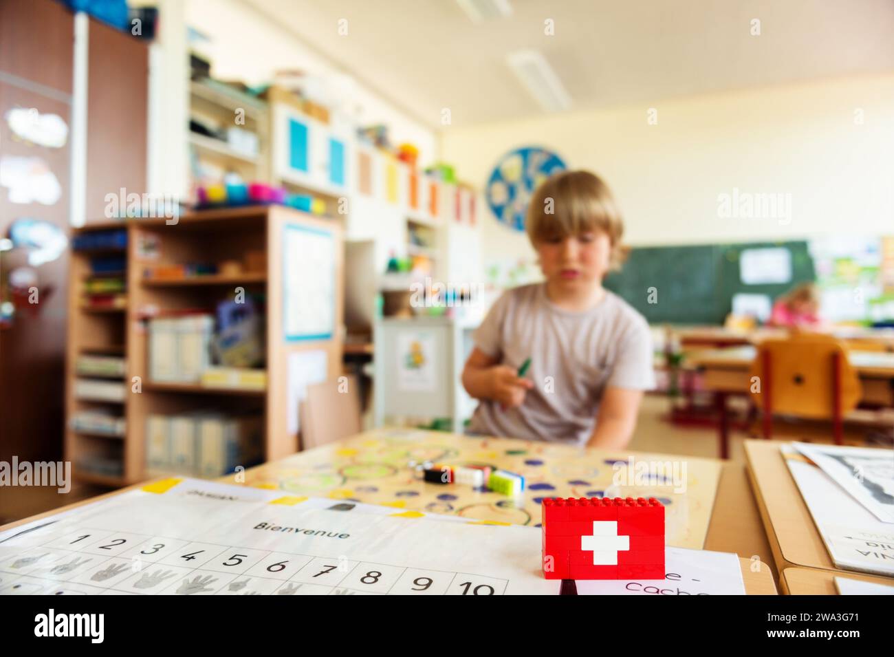 Background with cute little boy working in classroom, self made swiss flag, swiss primary education Stock Photo