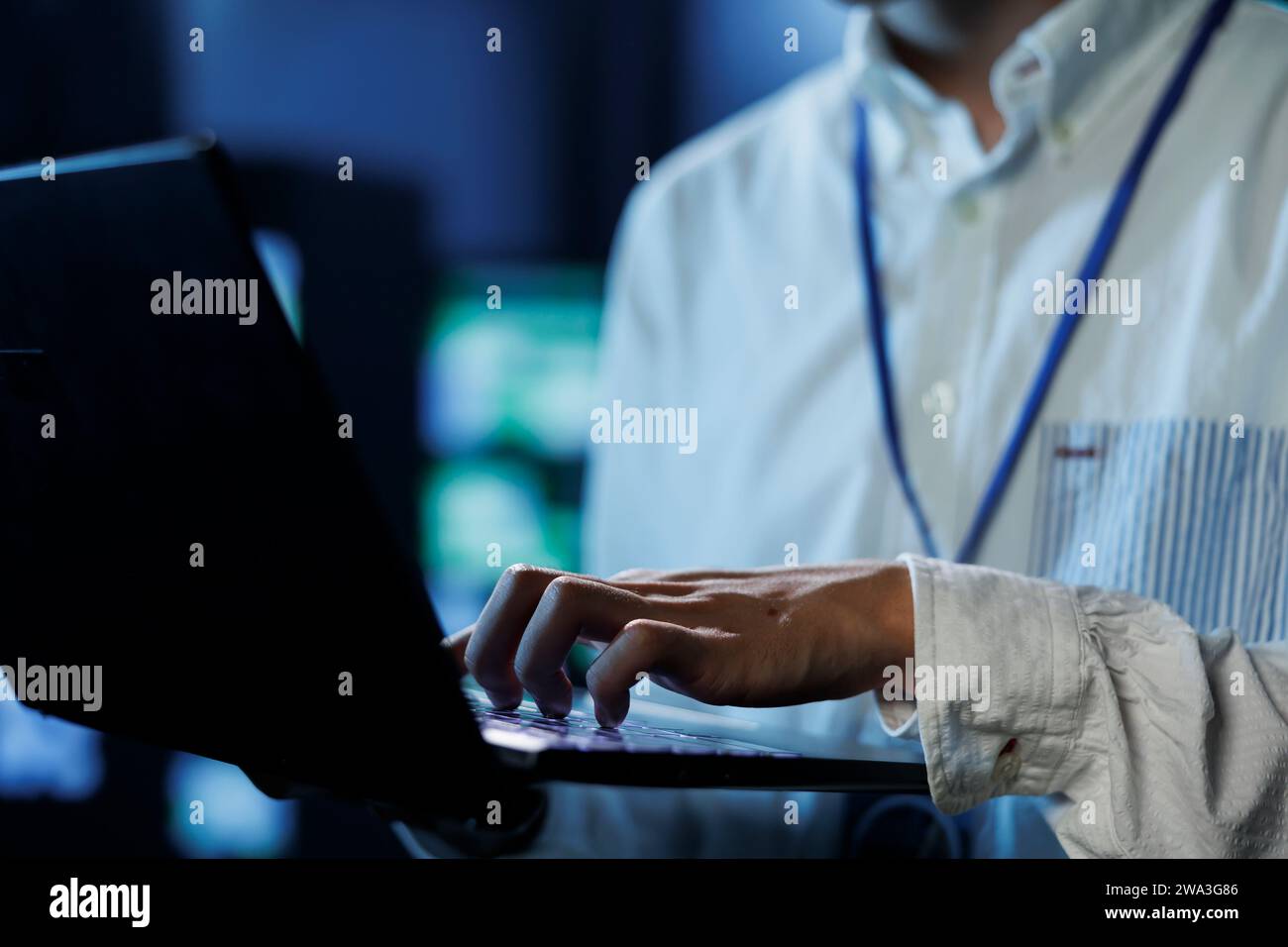 Man between server hub rows providing processing resources for businesses worldwide, blurry background. Scientist fixing data center mainframes tasked with managing massive databases, close up Stock Photo