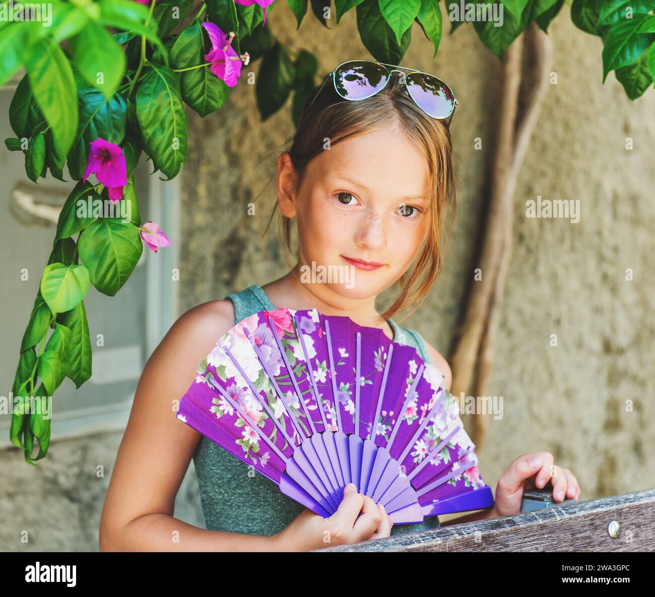 summer-portrait-of-pretty-7-8-year-old-girl-with-purple-fan-stock-photo