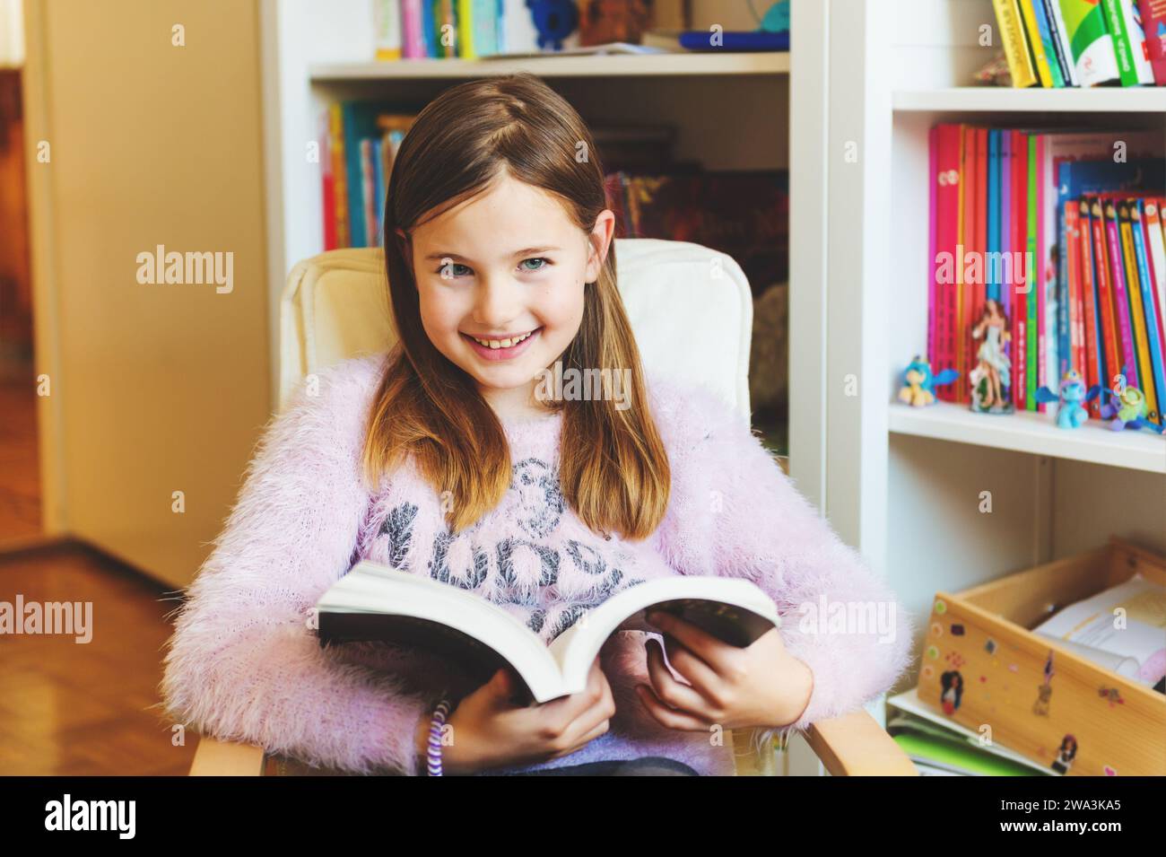Portrait of 8-9 year old kid girl reading book at home Stock Photo