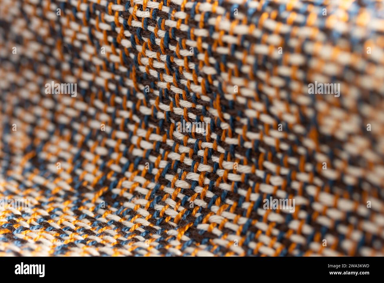 draped, multi-color woven cloth with orange, brown, cream and blue, close up detail macro shot with shallow depth of field Stock Photo