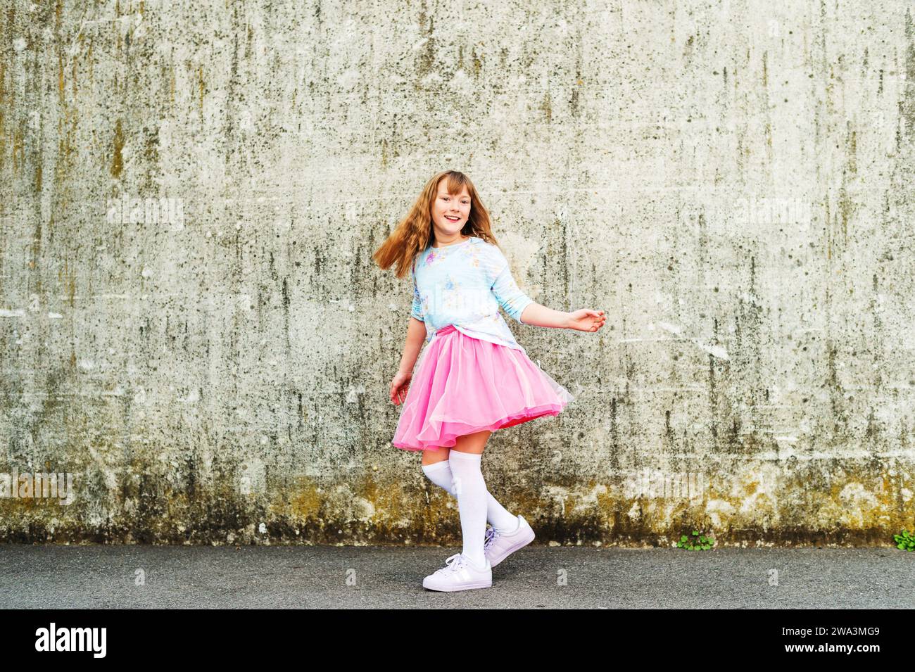 Happy little girl dancing on the street, wearing beautiful tutu skirt and high over knee socks Stock Photo