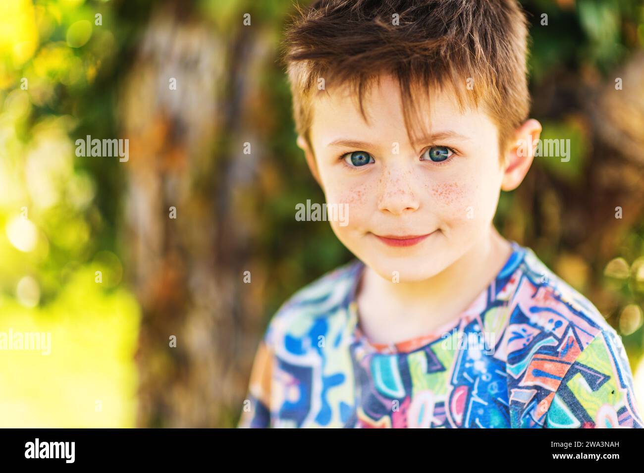 Outdoor close up portrait of adorable 5-6 year old red-haired boy with freckles on his face Stock Photo