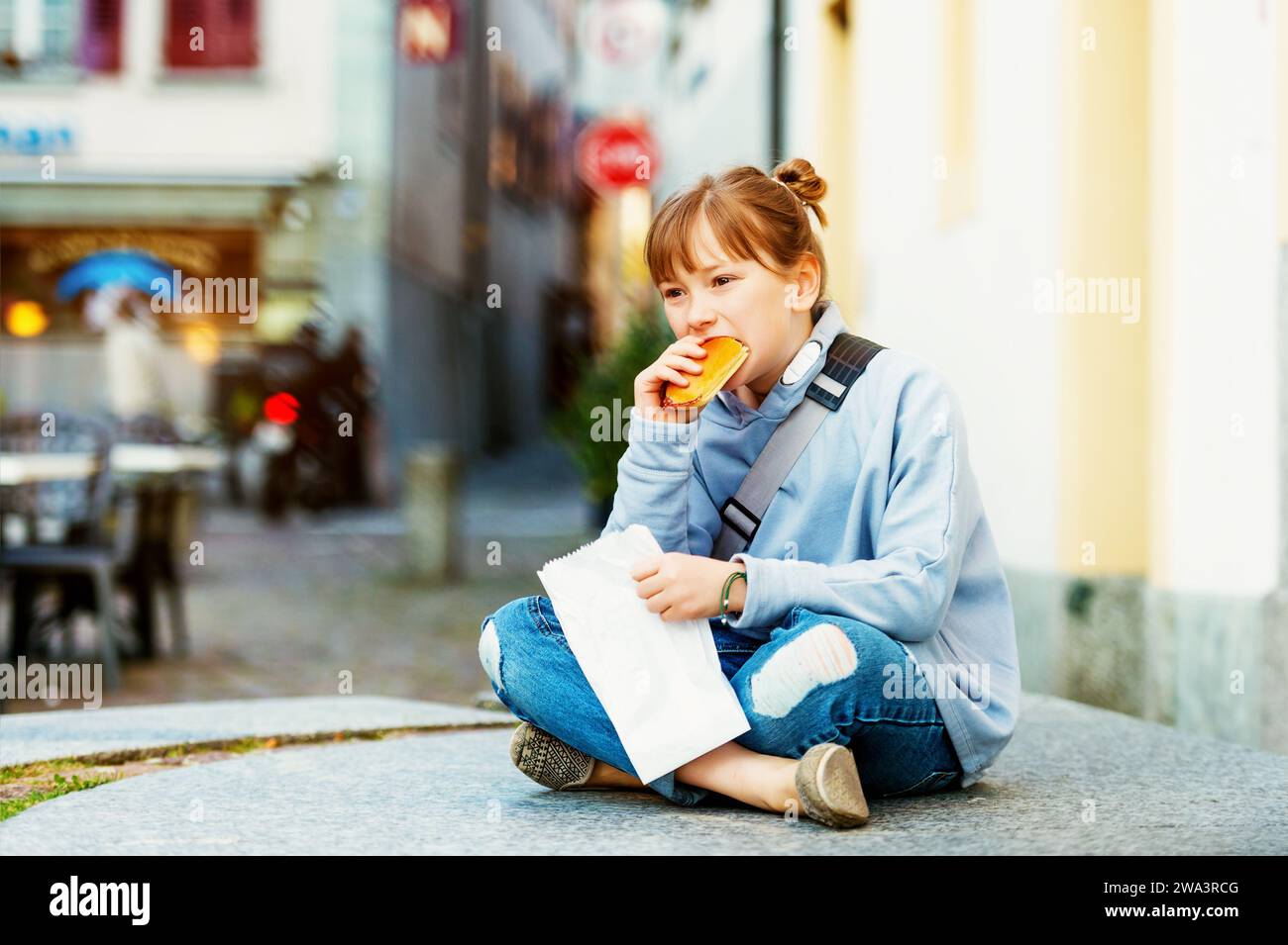 Adorable kid girl eating salami sandwich during school break Stock Photo