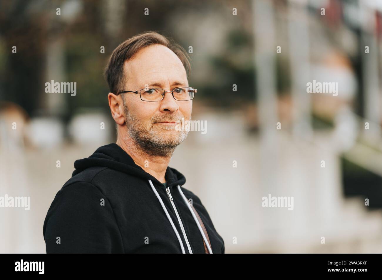 Outdoor portrait of 50 year old man wearing black hoody and eyeglasses Stock Photo