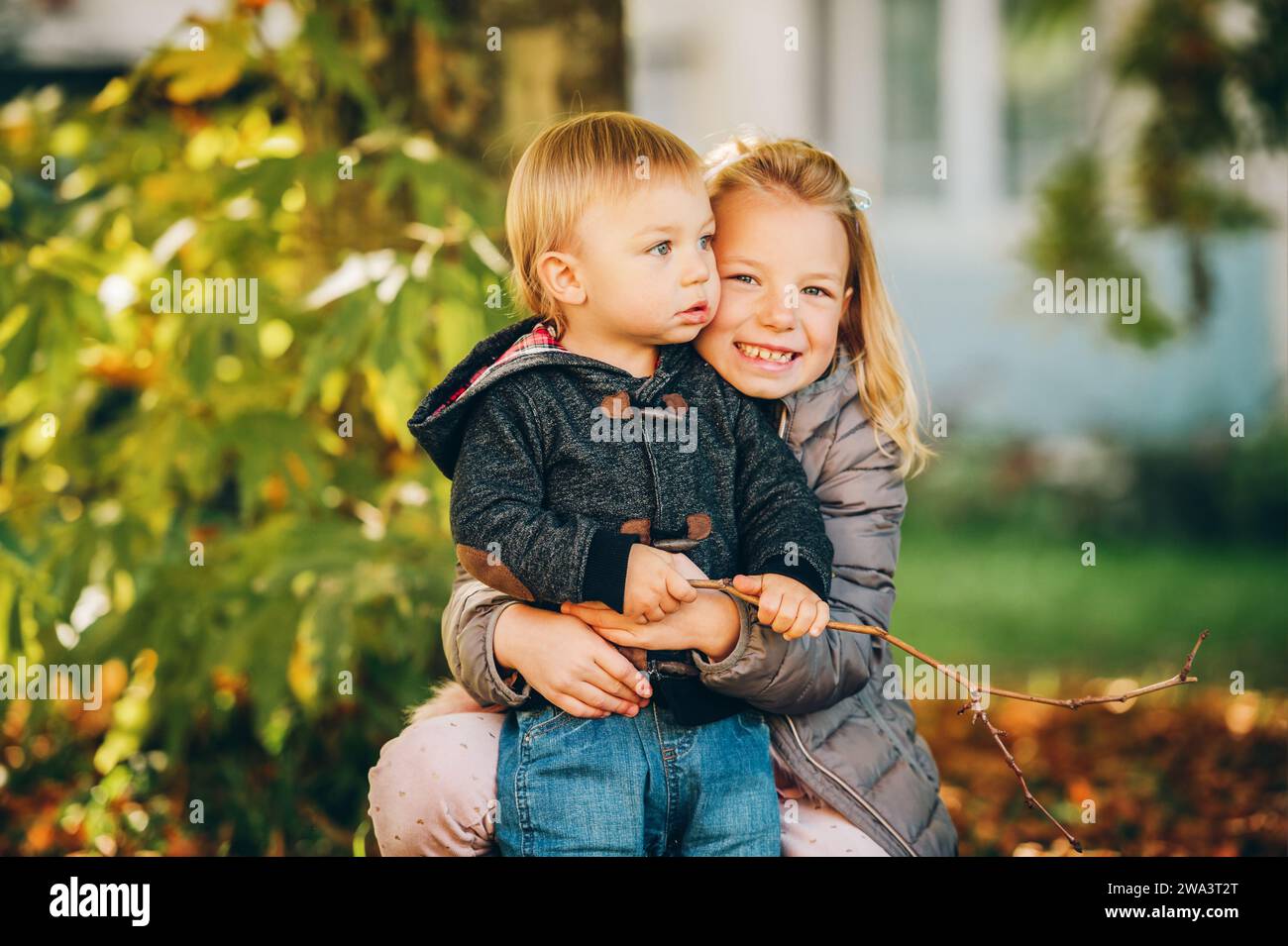 Small Sibling Outdoor autumn portrait of two happy kids, big sister and small brother ...