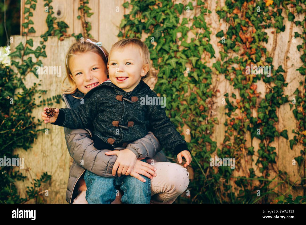 Small Sibling Outdoor autumn portrait of two happy kids, big sister and small brother ...