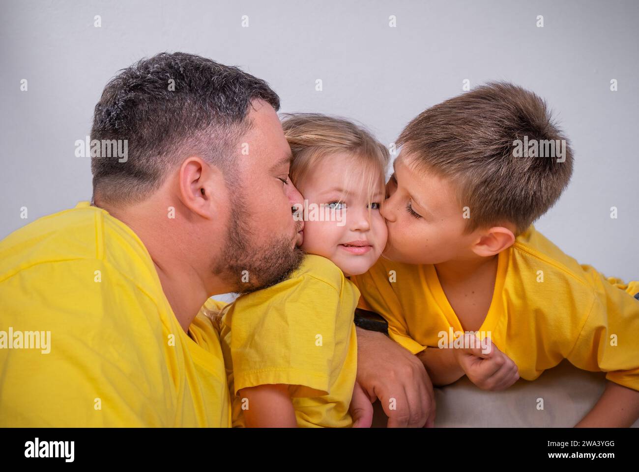 Family portrait. Dad and brother kiss the girl from different sides Stock Photo