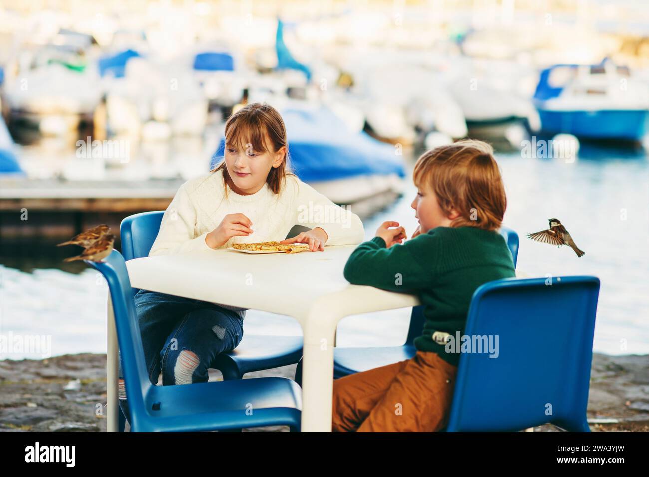 Cute little kids eating pancakes in a cafe, feeding birds Stock Photo