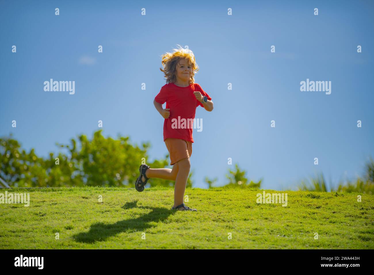 Cute boy running on green grass and blue sky. Healthy sport activity ...