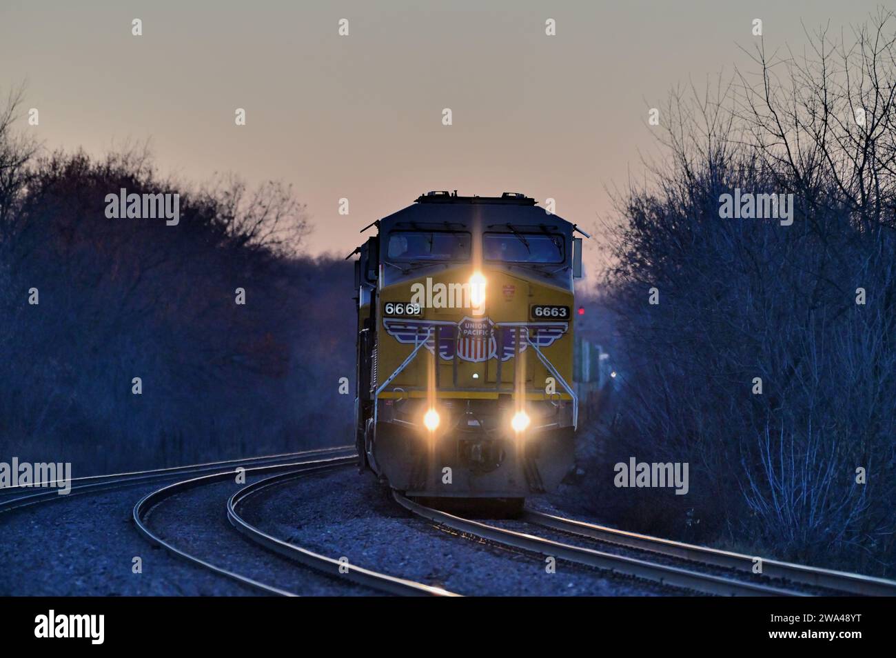 Winfield, Illinois, USA. A locomotive leads a Union Pacific intermodal freight train into a curve at dusk. Stock Photo