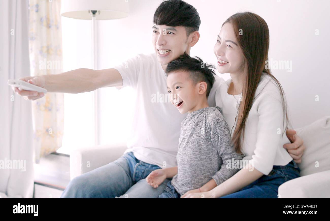 Happy Asian family watching TV together at hom Stock Photo