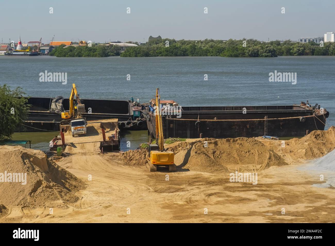 An excavator is loaded into a river vessel barges sand soil transportation of construction materials and materials along the river Stock Photo