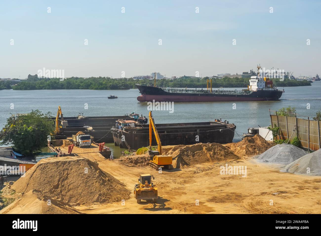 Excavator is loaded into a river vessel barges sand soil transportation of construction materials and materials along the river. Oil tanker floats nea Stock Photo