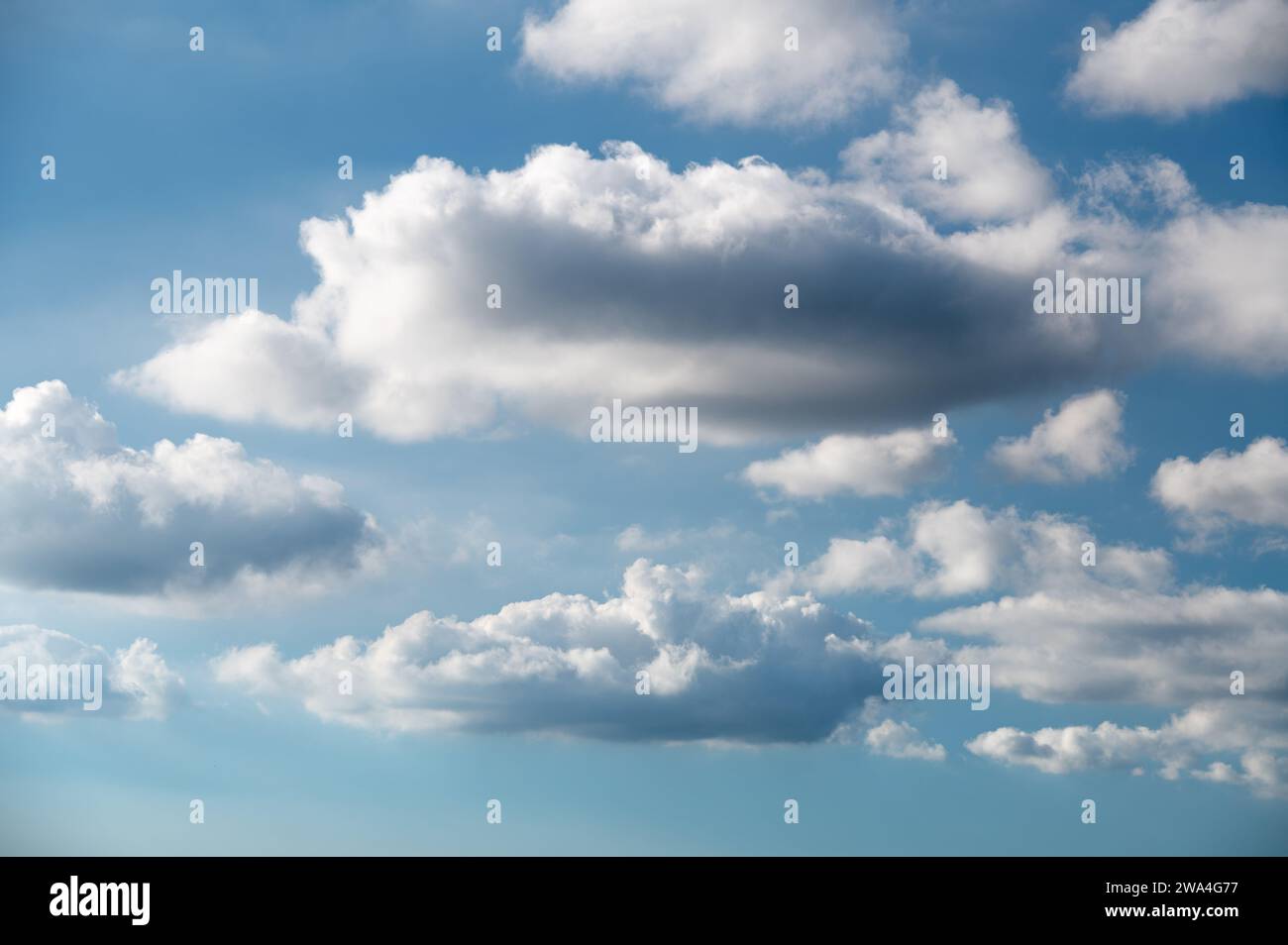 This is a tranquil scene of fluffy white clouds scattered across a deep blue sky, evoking a sense of calm and openness. Ideal for backgrounds. Stock Photo