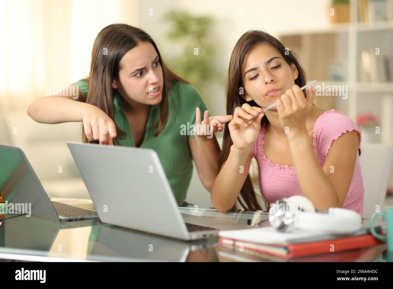 Angry student scolding to her lazy classmate who is wasting time at home Stock Photo
