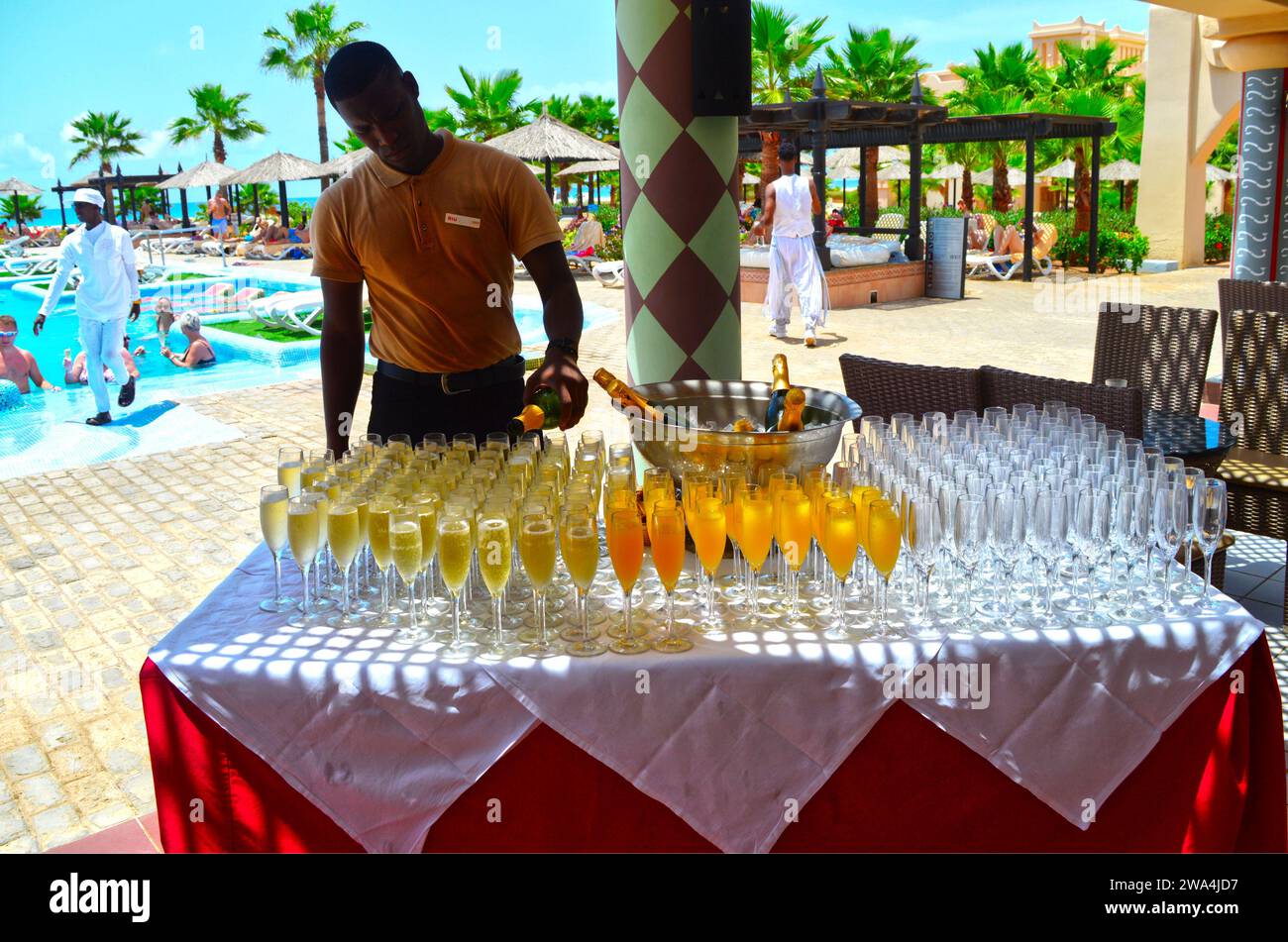 RIU Touareg hotel pouring Prosecco and Bucks fizz wine for the tourists at the bar near the swimming pool Stock Photo