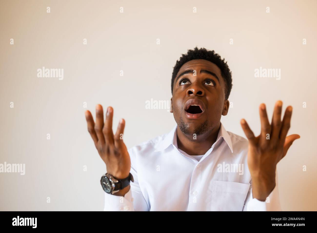 Portrait of young businessman who is disappointed and anxious. He is praying. Stock Photo