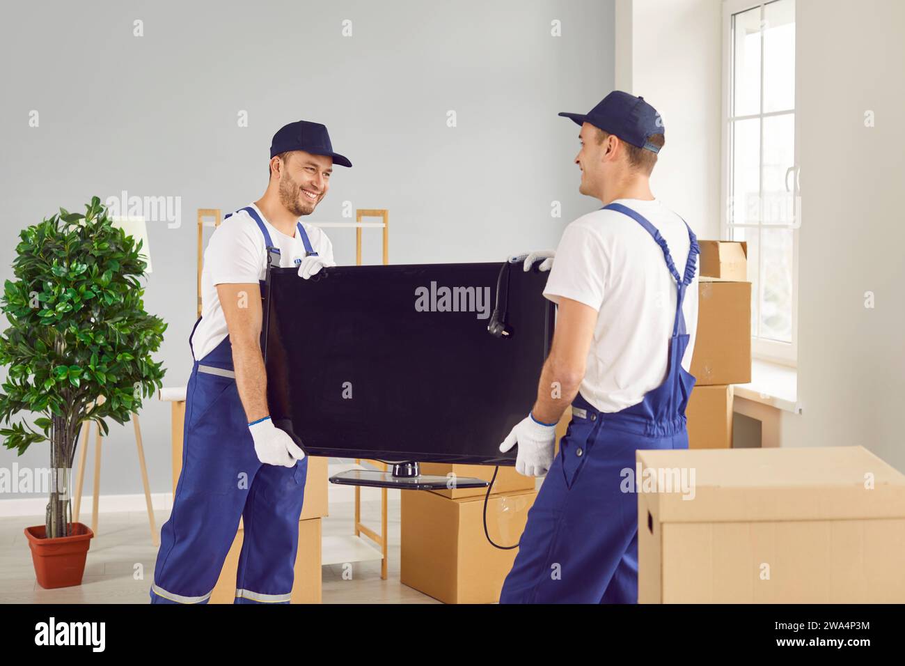 Two Movers Delivering Television during Home or Office Relocation Stock Photo