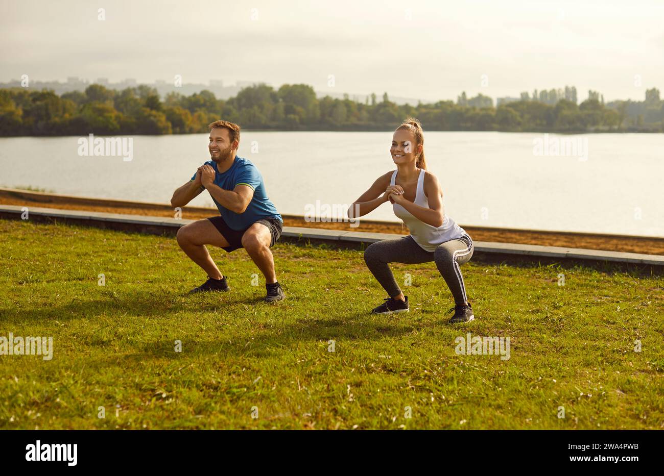 Active sporty young couple man and woman doing stretching exercising in nature. Stock Photo