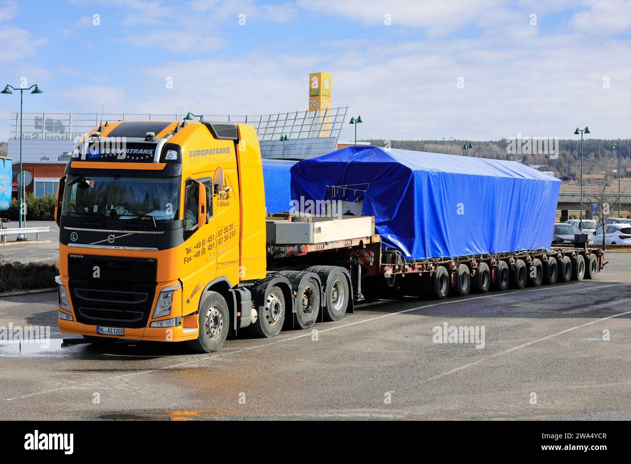 Yellow Volvo FH 540 truck in front of heavy load on multi-axle low loader trailer parked on truck stop. Oversize load. Salo, Finland. March 31, 2019. Stock Photo