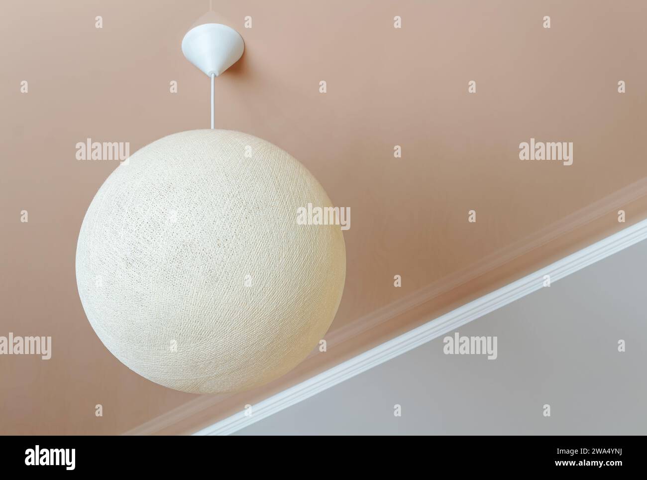 Ceiling lamp in the form of a wicker ball. Minimalist room interior. Stock Photo