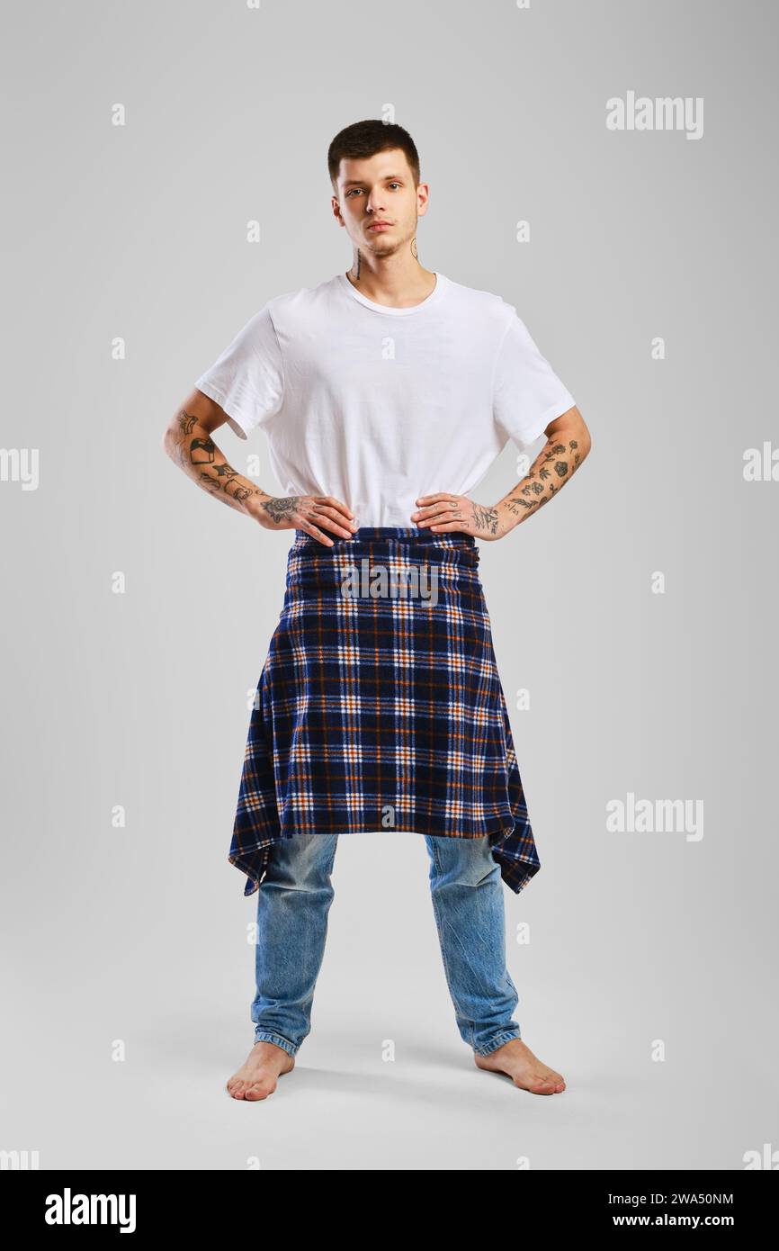 Young cocky man in t-shirt, jeans and checkered shirt tied at the waist Stock Photo