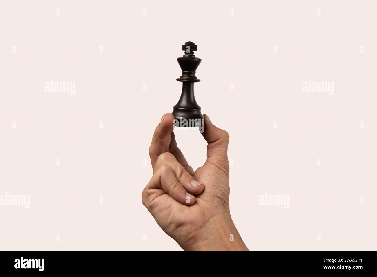 Black male hand holding a queen chess figure isolated Stock Photo