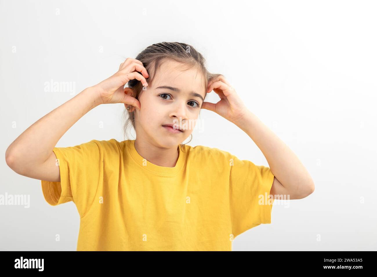 Little girl thinks holding her head on a white background isolated ...
