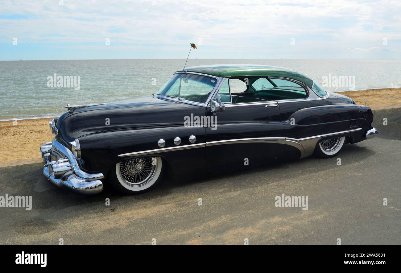 Classic Black Buick Eight motorcar on seafront promenade beach and sea in background. Stock Photo