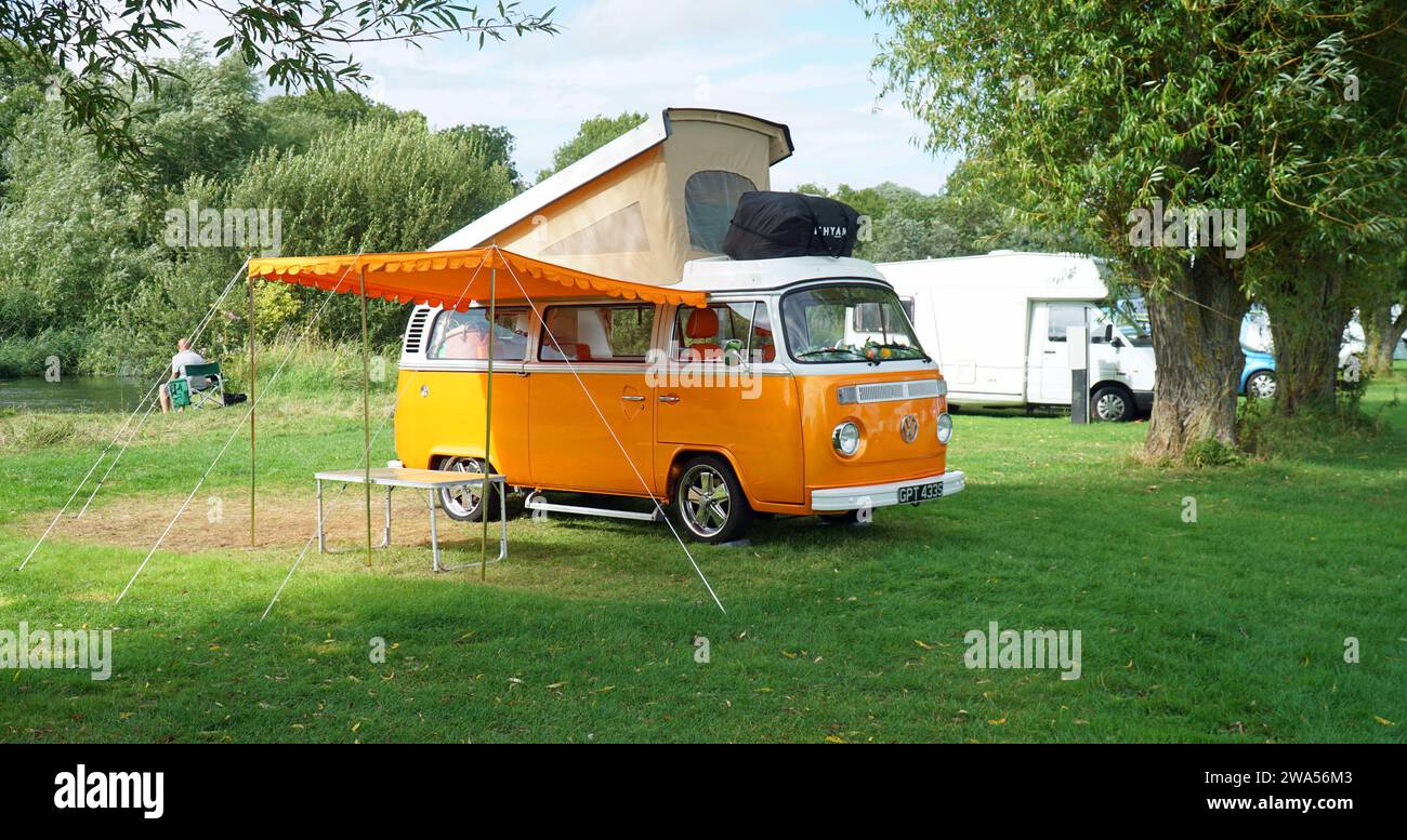 Classic  Orange  Volkswagen  Camper Van parked on Camp Site  by river with top up and Awning . Stock Photo
