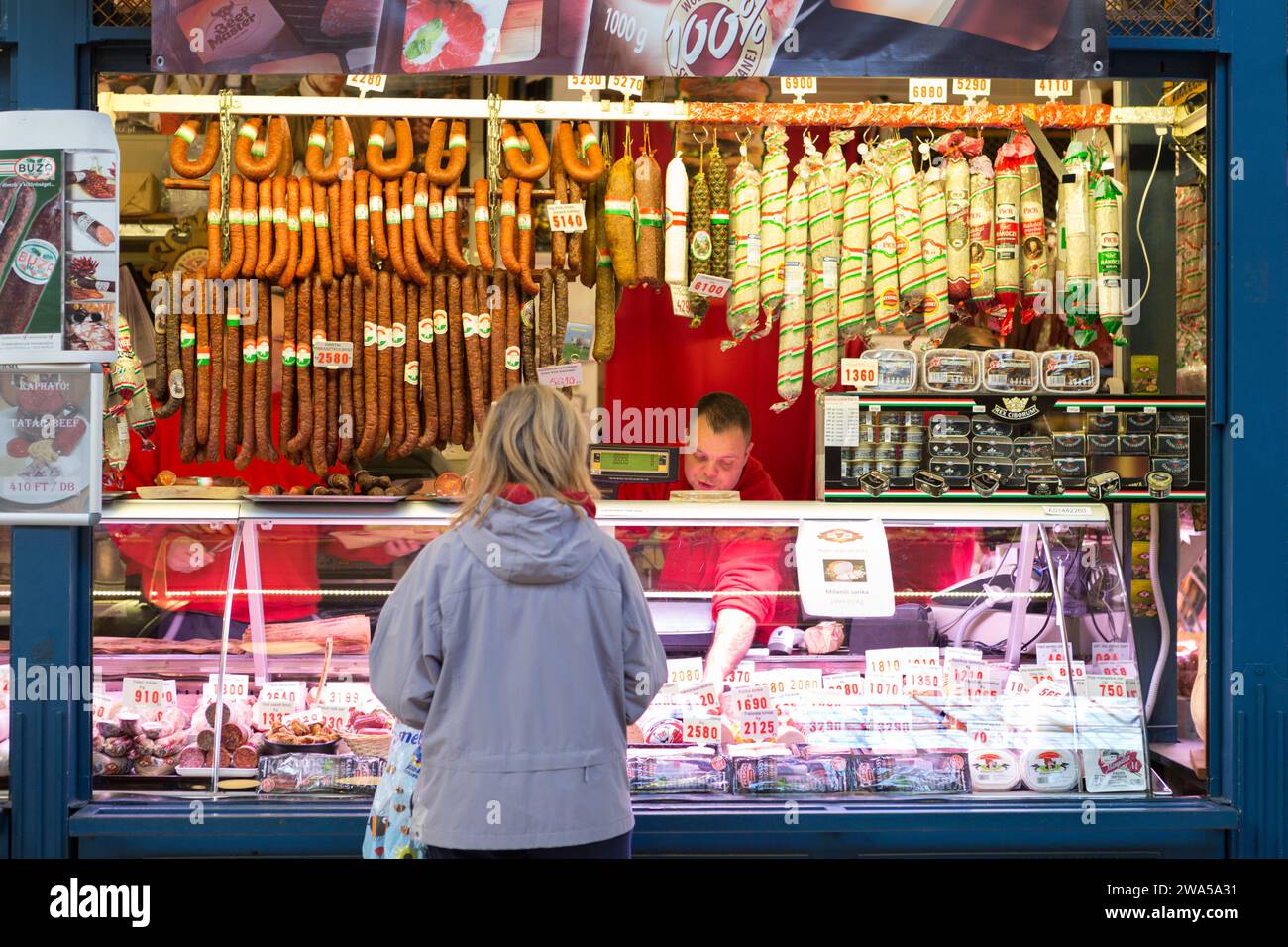 Hungary, Budapest, a local being served at a traditional meat stall in the Central indoor City Market. Stock Photo