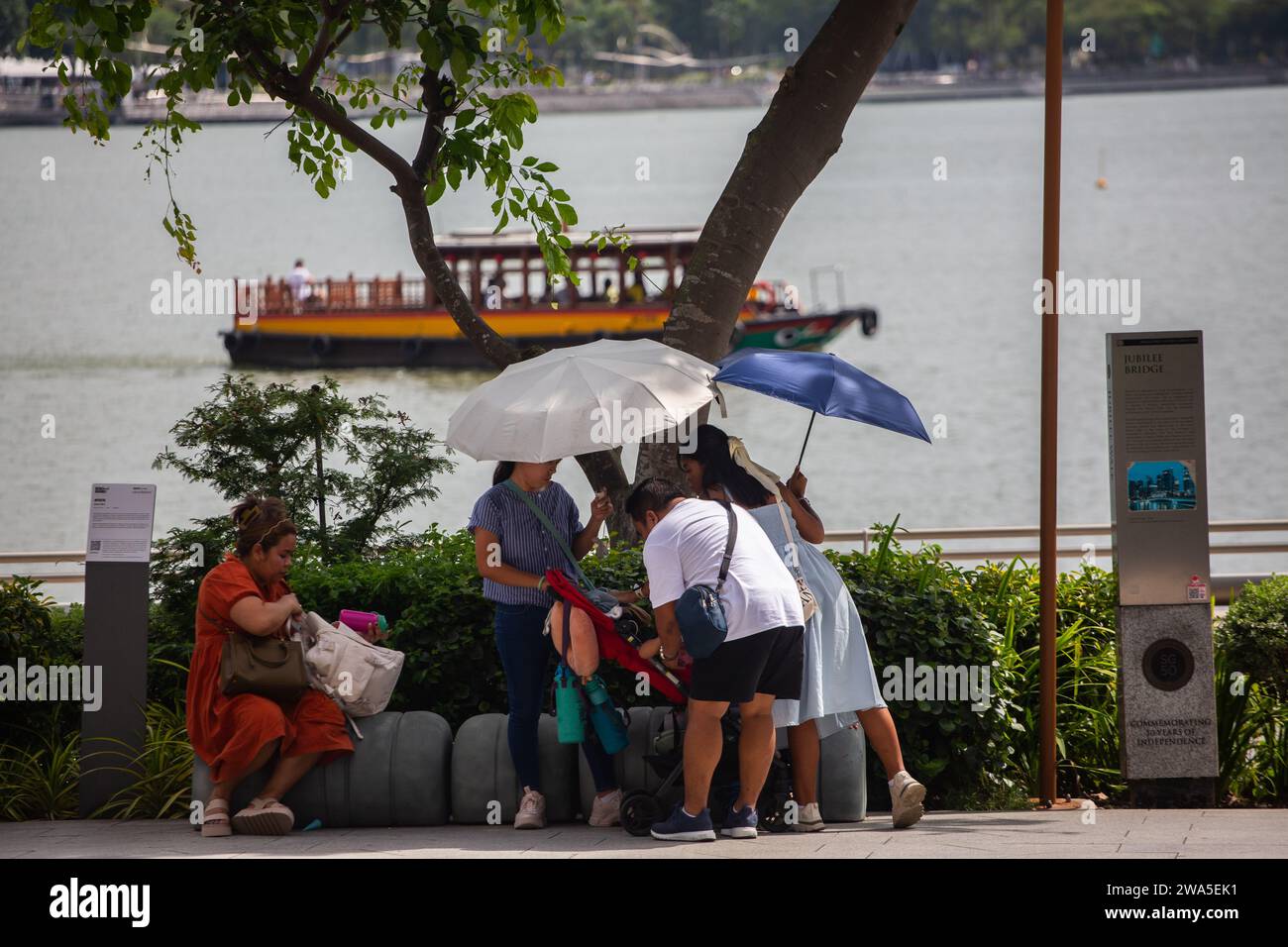 Tourists holding umbrella and stay under the shade in Singapore hot weather climate. January