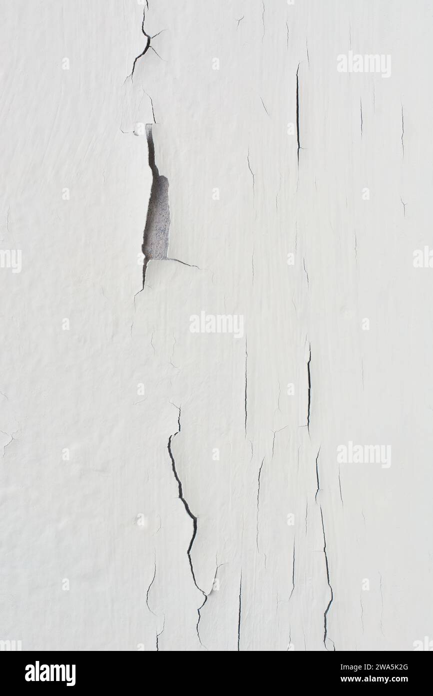 close-up of cracked wall, white wall surface with paint peeling off, non standard interiors in vertical orientation Stock Photo