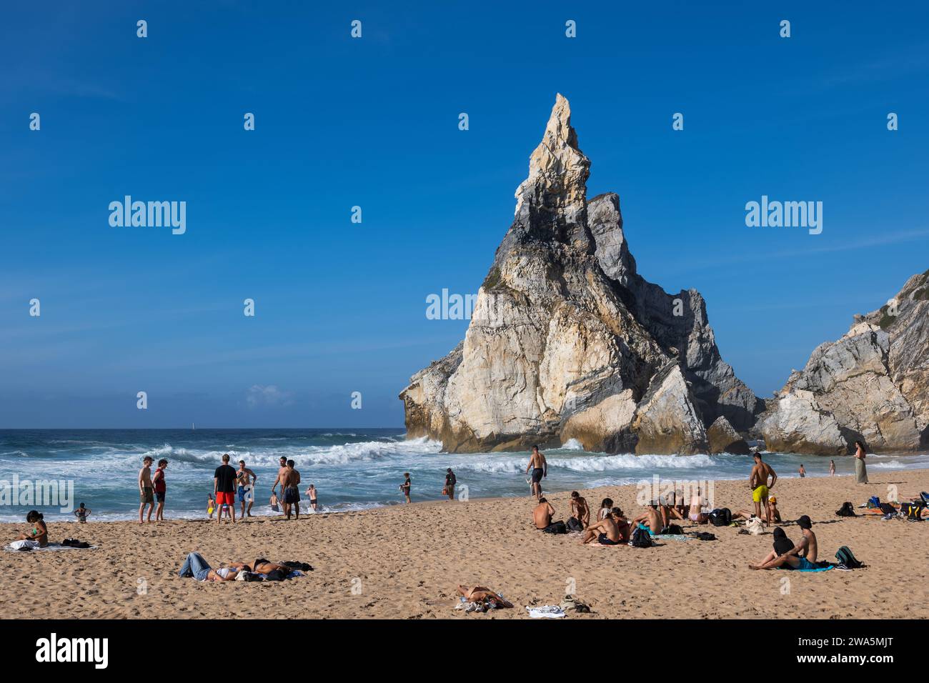 Praia da Ursa, Portugal - October 14, 2023 - People sunbath at remote Ursa Beach by the Atlantic Ocean with striking coastal rock formations. Stock Photo
