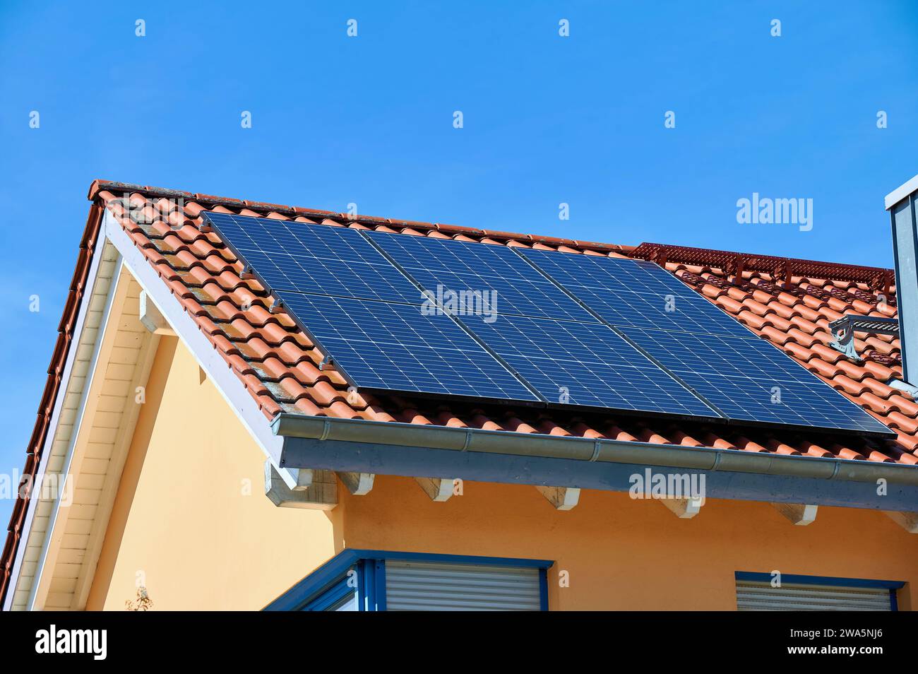 Solar panels on the roof of a newly built detached house against a blue sky Stock Photo