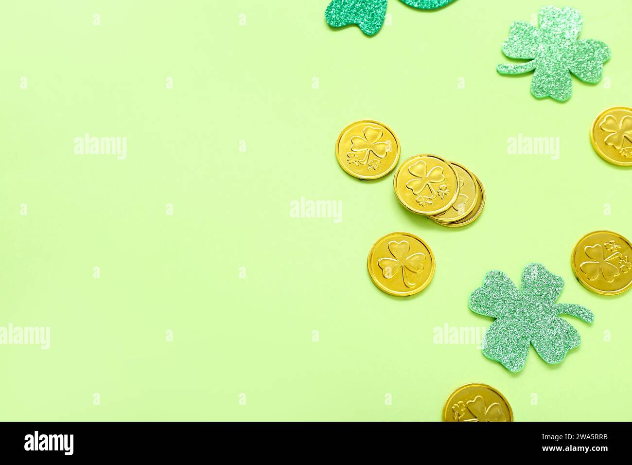 Golden coins with paper clovers on light green background. St. Patrick ...