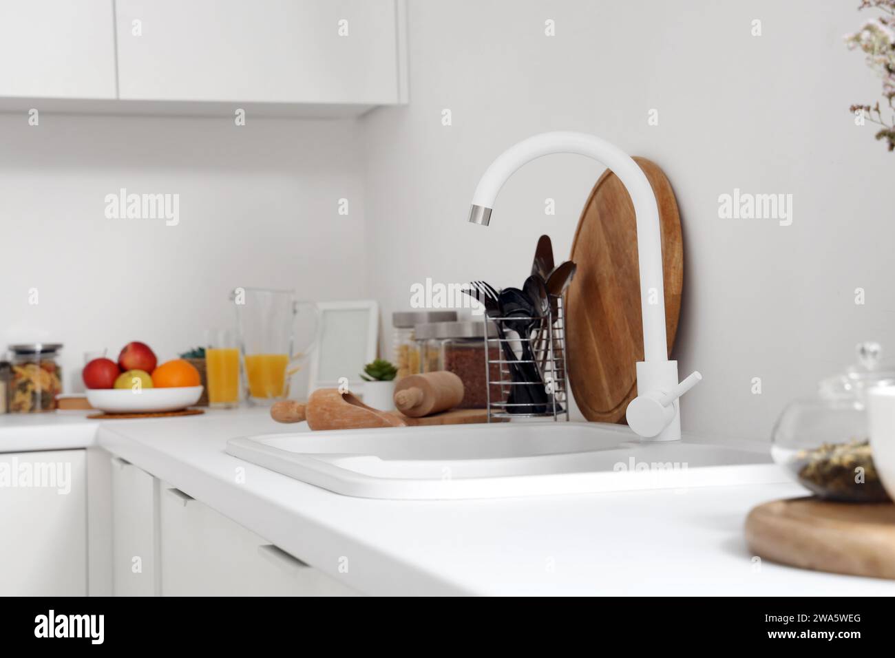 White counters with sink and utensils in interior of modern kitchen ...
