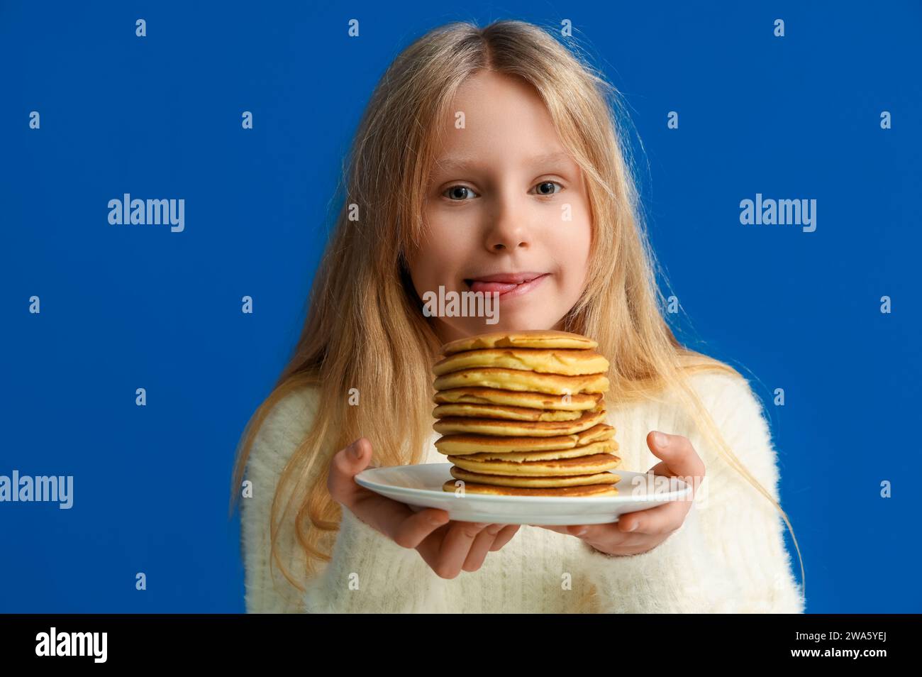Hungry little girl with tasty pancakes on blue background, closeup Stock Photo