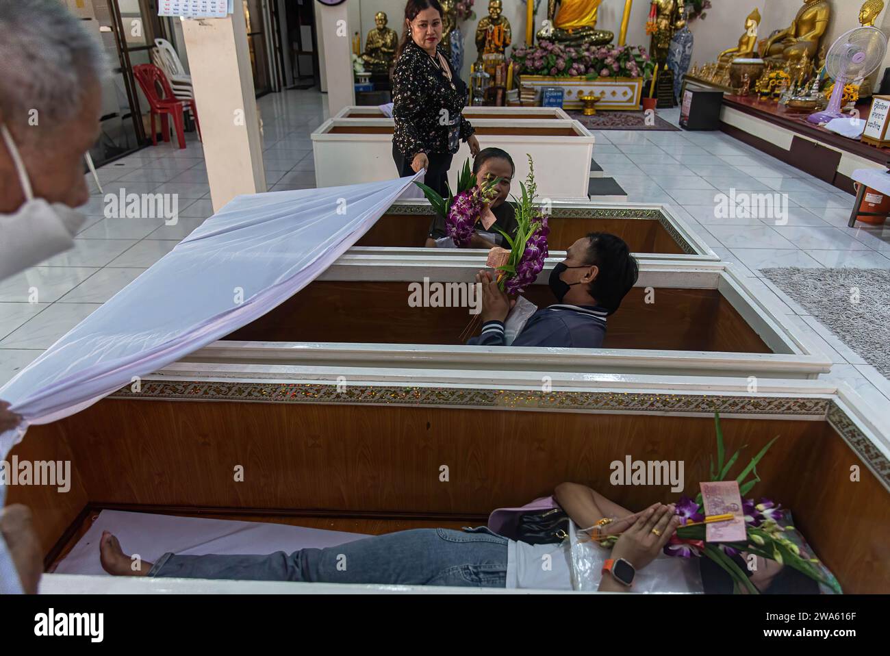 Buddhist devotees lay inside coffins to perform a resurrection ceremony