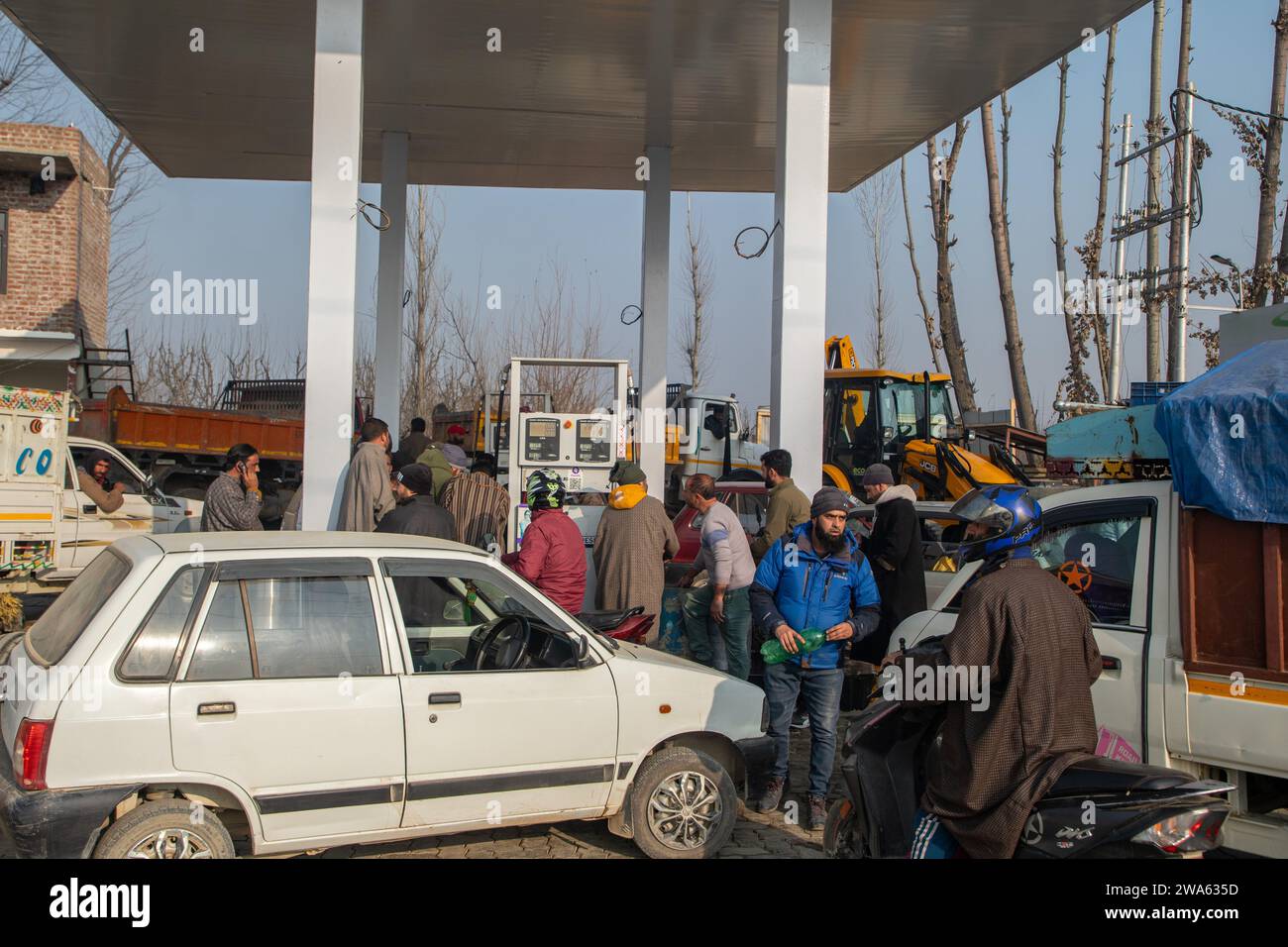 People wait with their vehicles in a queue to refill fuel tanks at a ...