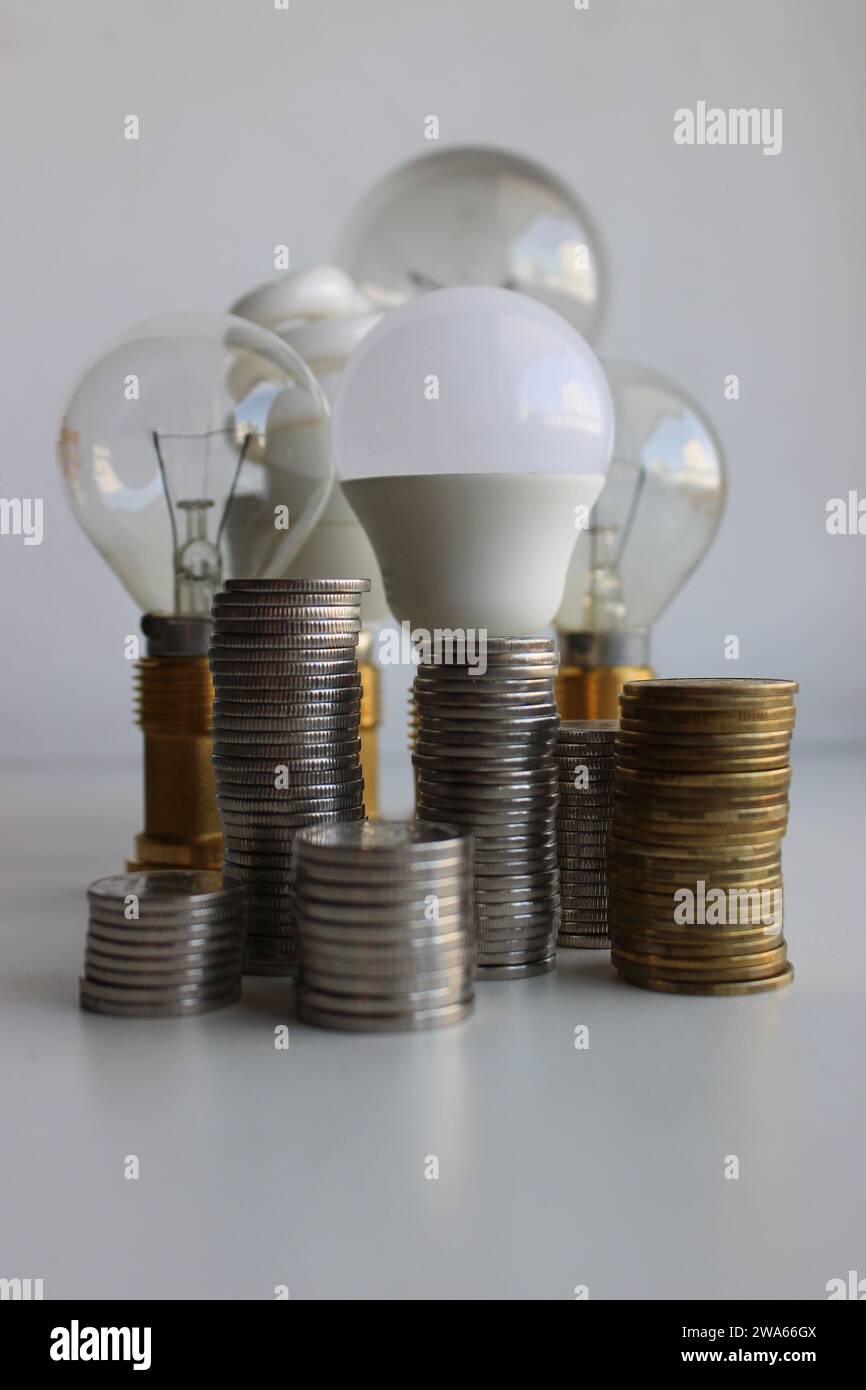 Columns of coins in front of different bulb lamps as an illustration electricity cost Stock Photo