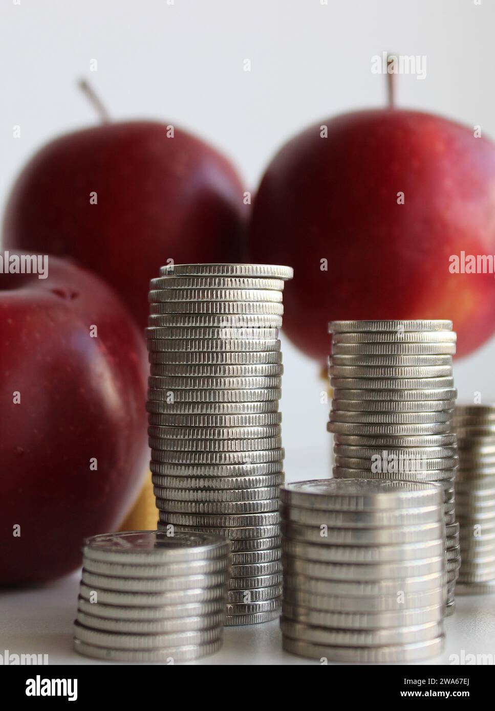 Concept photo of fruits cost. Three red apples and columns of coins closeup stock photo Stock Photo