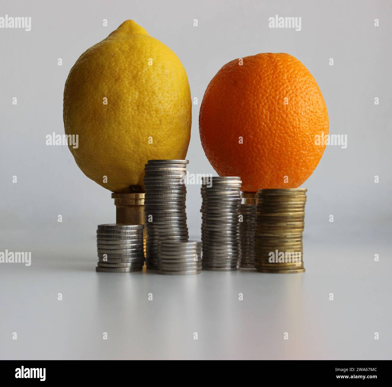 Columns of coins in front of lemon and orange fruits as an illustration
