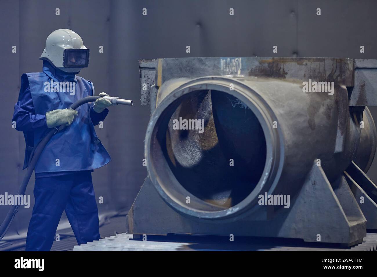 worker processes workpiece with sandblasting tool in factory, selective