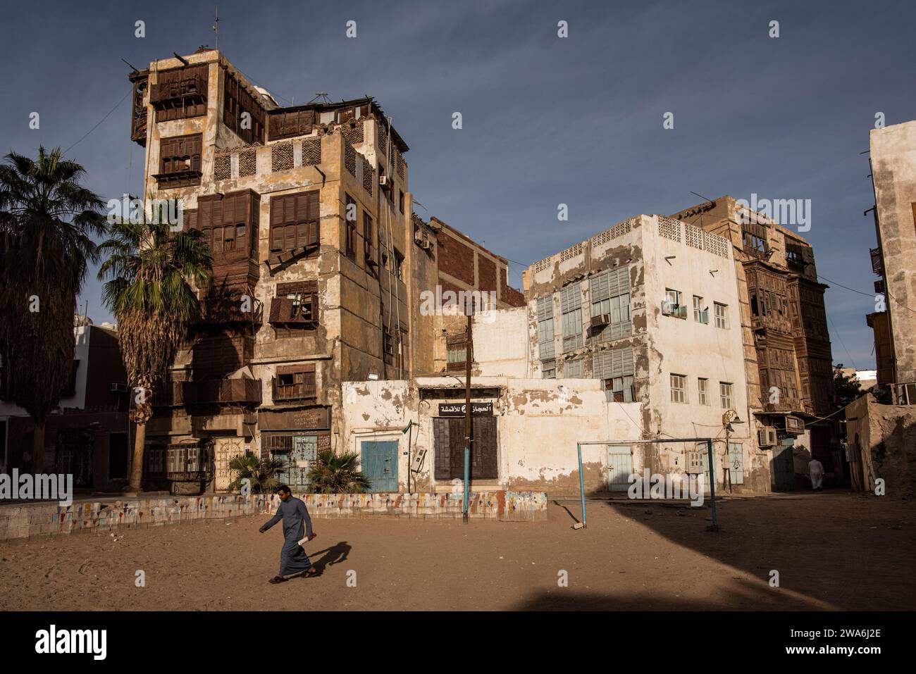 Man Walking Past Tall Buildings in in Al Balad, Historical district of Jeddah, Saudi Arabia Stock Photo