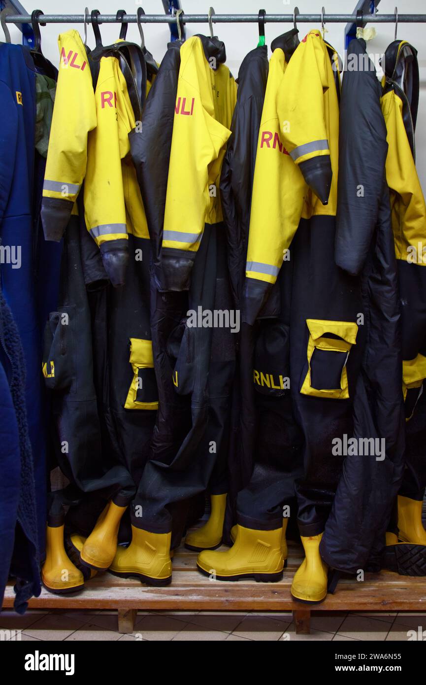 RNLI Dry Suits And Boots Hanging On A Rail At Mudeford Lifeboat Station Stock Photo