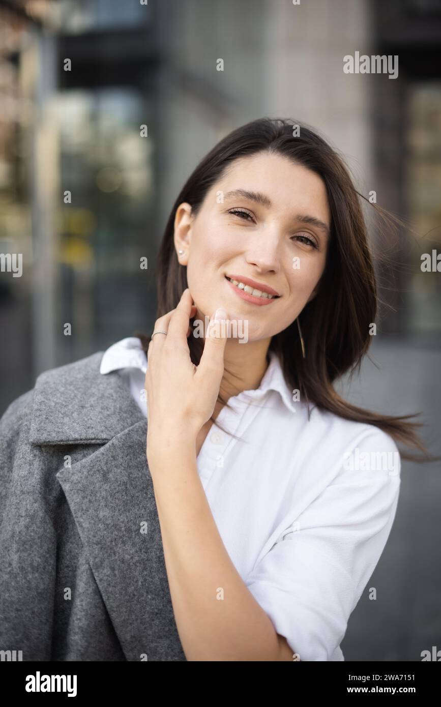 young woman posing on city street, walking and looking at camera Stock